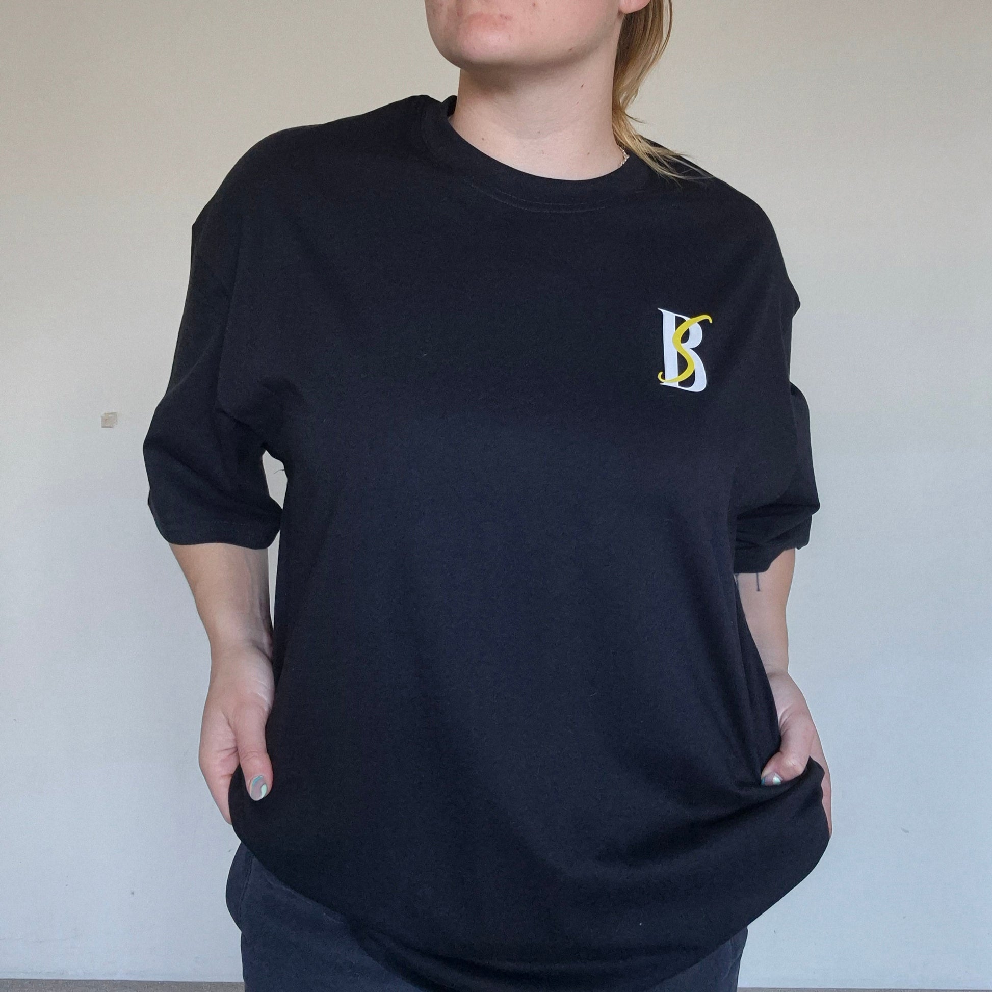 Person wearing a black sweatshirt with a logo against a plain background