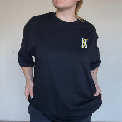 Person wearing a black sweatshirt with a logo against a plain background
