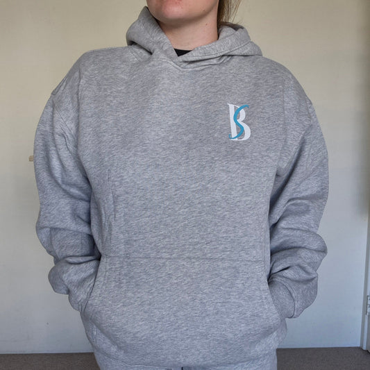 Person wearing a gray hoodie with a logo on a plain background